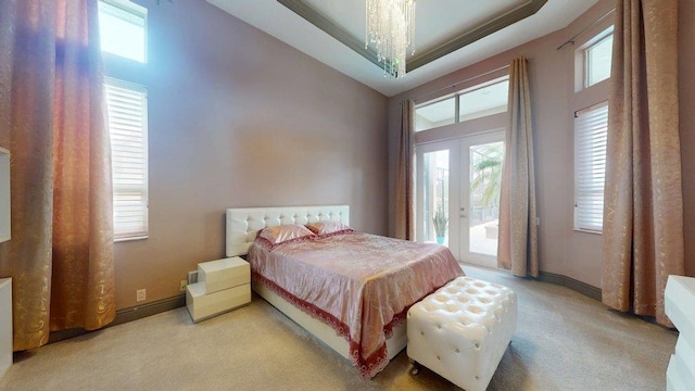 bedroom featuring access to exterior, a towering ceiling, light colored carpet, and french doors