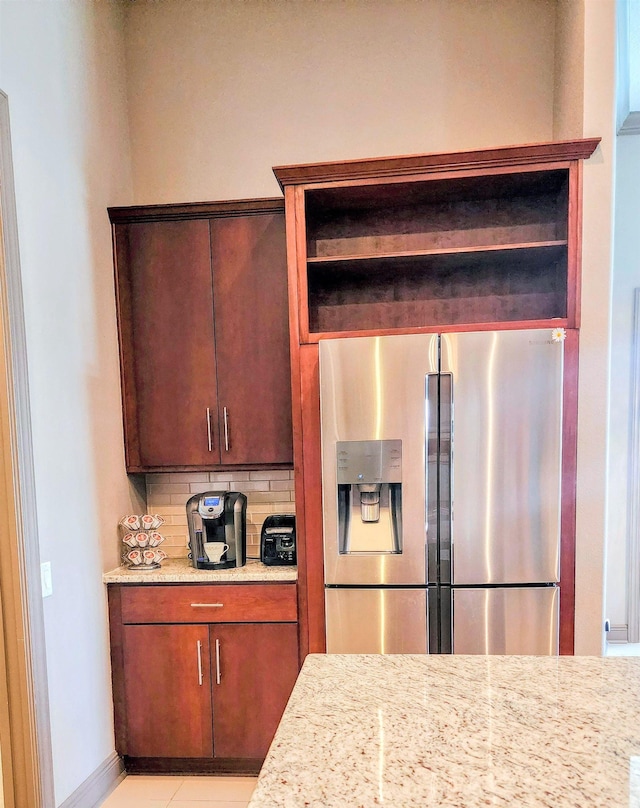 kitchen with stainless steel fridge, backsplash, and light stone counters