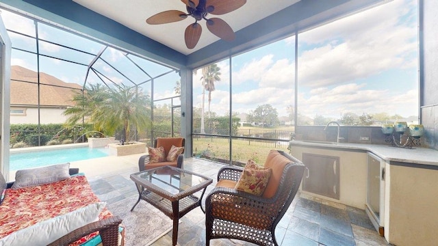 sunroom / solarium featuring ceiling fan, plenty of natural light, and sink