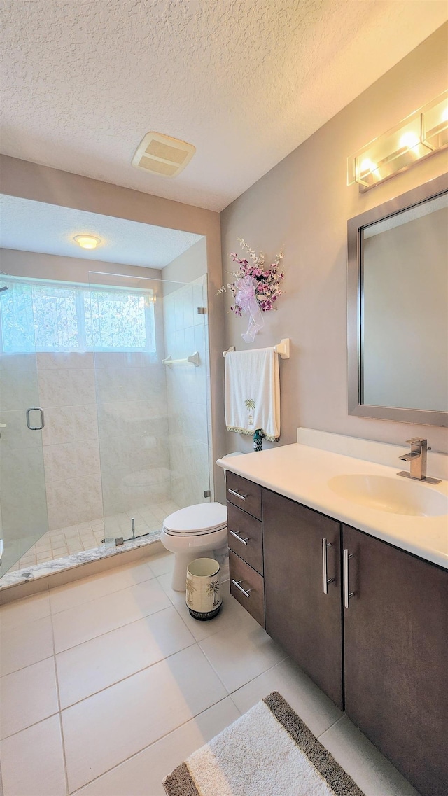 bathroom featuring an enclosed shower, vanity, a textured ceiling, tile patterned flooring, and toilet