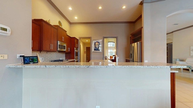 kitchen with appliances with stainless steel finishes, backsplash, kitchen peninsula, crown molding, and light stone countertops