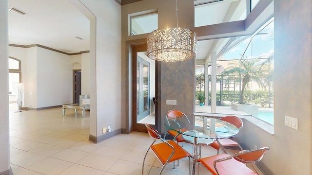 dining space featuring a notable chandelier, crown molding, and light tile patterned flooring