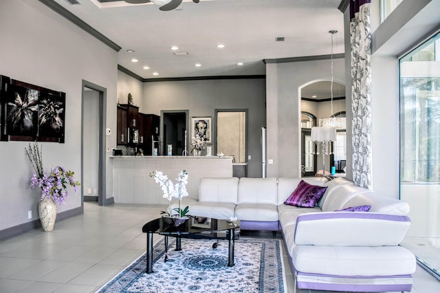 tiled living room with ceiling fan and ornamental molding