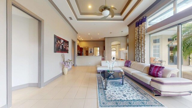 living room featuring light tile patterned floors, a tray ceiling, and ornamental molding