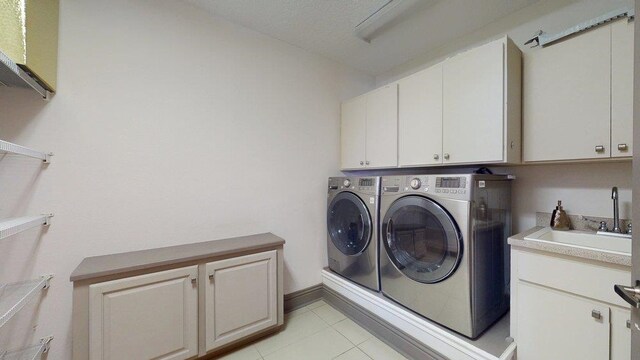 laundry room with cabinets, light tile patterned floors, a textured ceiling, and washer and clothes dryer