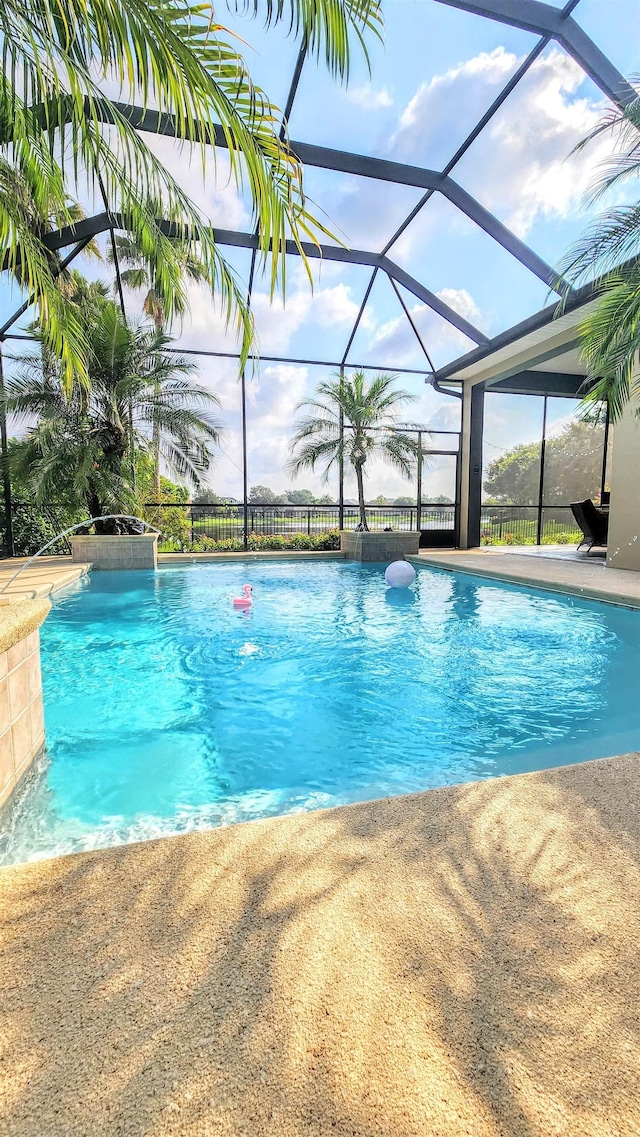 view of swimming pool with glass enclosure and pool water feature