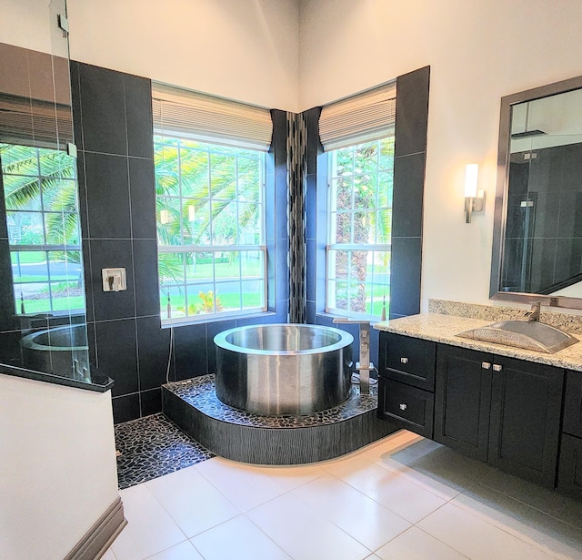 bathroom featuring tile patterned floors, plus walk in shower, vanity, and tile walls