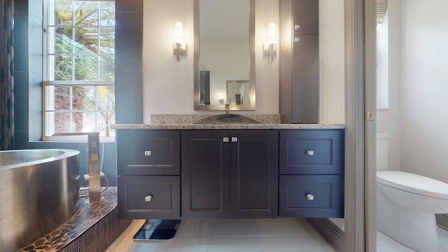 bathroom featuring vanity, tile patterned flooring, a bathing tub, and toilet