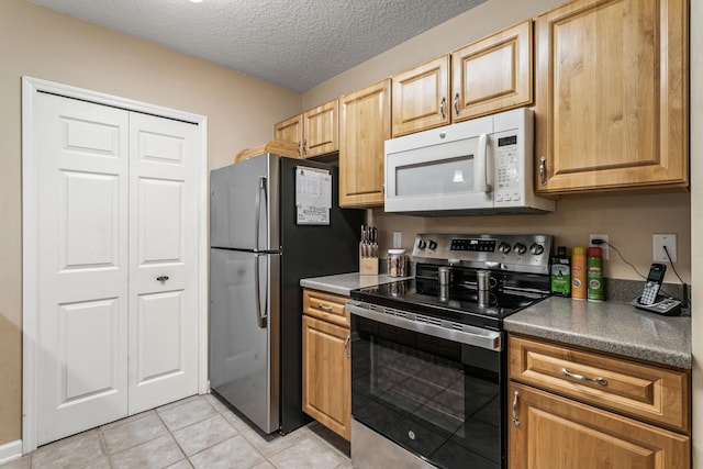 kitchen featuring light tile patterned floors, a textured ceiling, and stainless steel appliances