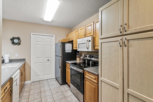 kitchen with appliances with stainless steel finishes, light brown cabinetry, a textured ceiling, sink, and light tile patterned floors