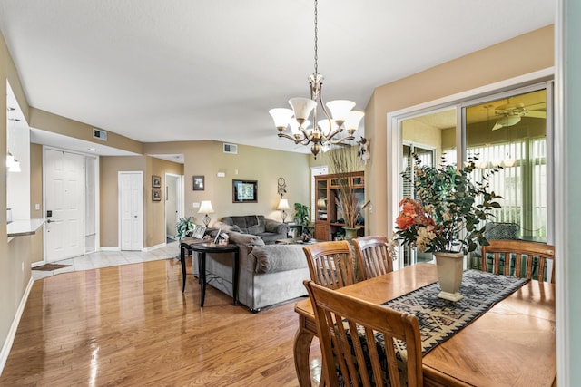 dining space with ceiling fan with notable chandelier and light wood-type flooring