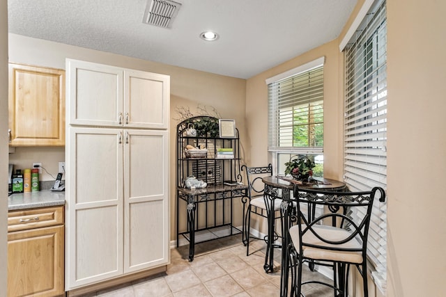 kitchen with light tile patterned floors, a textured ceiling, and light brown cabinetry