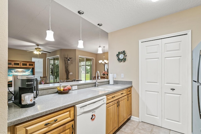 kitchen featuring sink, hanging light fixtures, white dishwasher, light tile patterned floors, and ceiling fan with notable chandelier