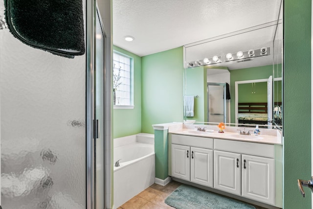 bathroom with vanity, tile patterned flooring, plus walk in shower, and a textured ceiling