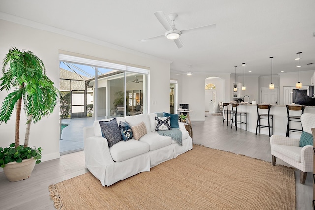 living room featuring ornamental molding, ceiling fan, light hardwood / wood-style flooring, and sink