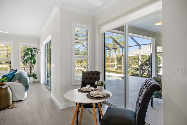 dining space featuring plenty of natural light, ornamental molding, and light wood-type flooring