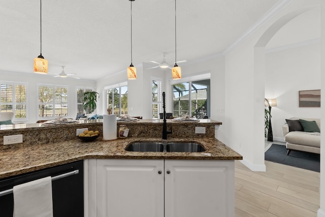 kitchen featuring white cabinets, dishwasher, decorative light fixtures, dark stone counters, and a healthy amount of sunlight