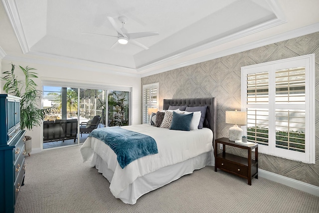 carpeted bedroom with ceiling fan, access to exterior, and a tray ceiling