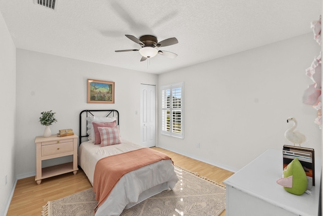 bedroom with ceiling fan, a textured ceiling, a closet, and light wood-type flooring