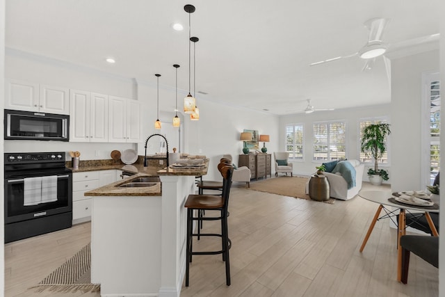 kitchen with decorative light fixtures, sink, white cabinetry, and black appliances