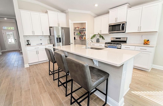 kitchen featuring lofted ceiling, a kitchen bar, appliances with stainless steel finishes, and white cabinetry