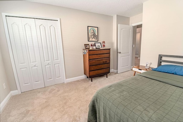 bedroom with a closet, a textured ceiling, and light colored carpet