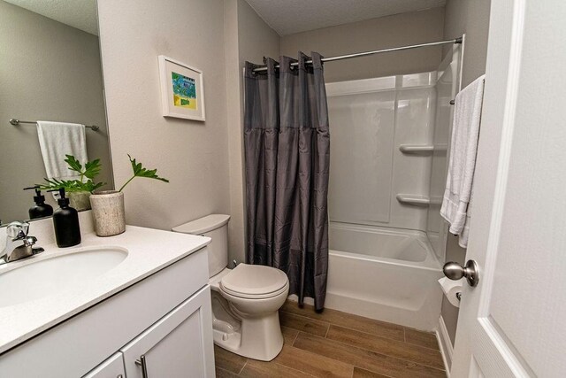 full bathroom featuring toilet, a textured ceiling, shower / bath combination with curtain, and vanity