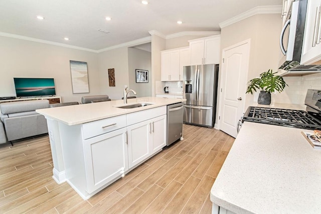 kitchen featuring stainless steel appliances, sink, white cabinets, an island with sink, and backsplash