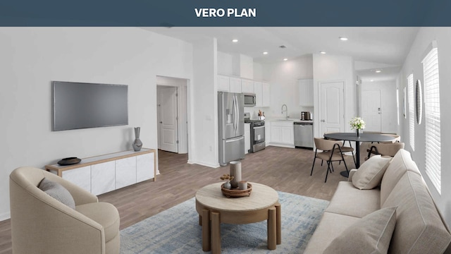 living room with hardwood / wood-style floors, high vaulted ceiling, and sink