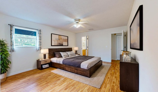 bedroom featuring light wood-style floors, a textured ceiling, baseboards, and a ceiling fan