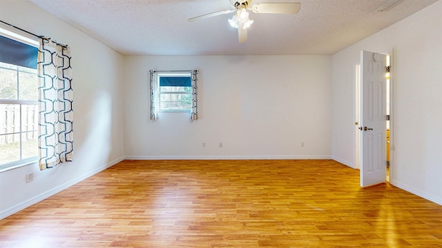 unfurnished room with light wood finished floors, a ceiling fan, visible vents, and a textured ceiling