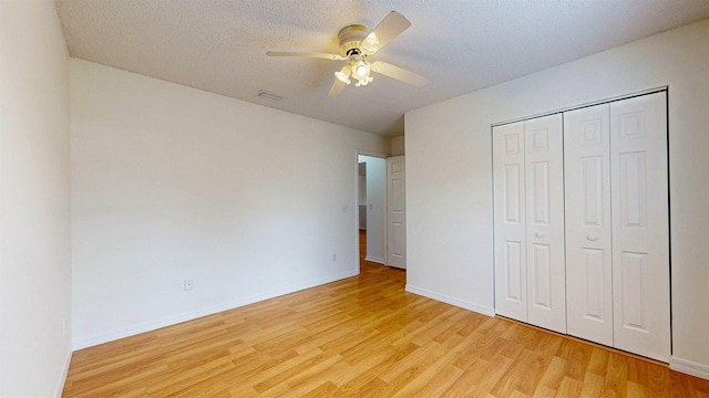 unfurnished bedroom featuring a closet, baseboards, light wood-style flooring, and a textured ceiling