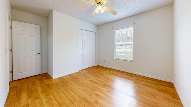 unfurnished bedroom with baseboards, light wood-style flooring, ceiling fan, a textured ceiling, and a closet