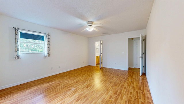 empty room with a textured ceiling, light wood finished floors, a ceiling fan, and baseboards