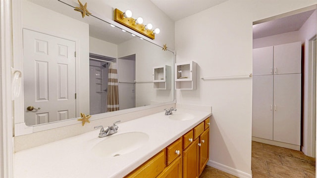 full bathroom featuring double vanity, curtained shower, baseboards, and a sink