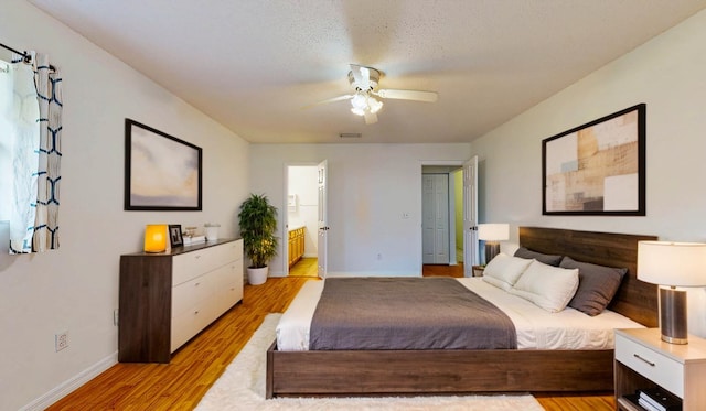 bedroom with visible vents, baseboards, a ceiling fan, light wood-style flooring, and ensuite bathroom