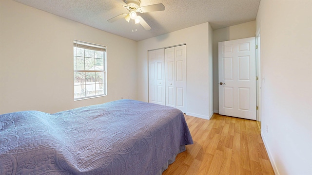 bedroom featuring light wood finished floors, a closet, a ceiling fan, a textured ceiling, and baseboards