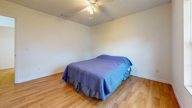 bedroom featuring light wood-type flooring, visible vents, ceiling fan, and baseboards