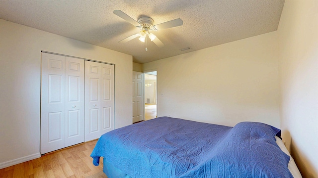 bedroom featuring baseboards, a ceiling fan, light wood-style flooring, a textured ceiling, and a closet