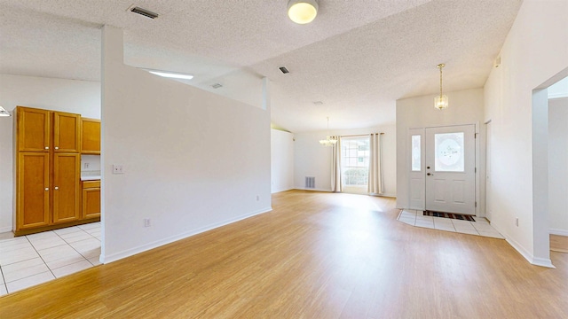 entryway featuring light wood-type flooring, visible vents, and vaulted ceiling