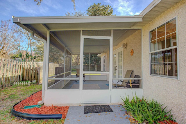 entrance to property with french doors, fence, and stucco siding