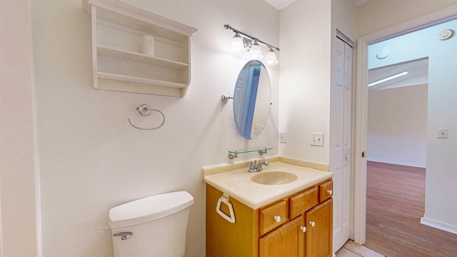 half bath with wood finished floors, vanity, toilet, and baseboards