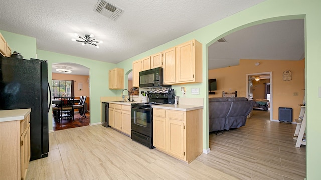 kitchen with black appliances, sink, vaulted ceiling, light wood-type flooring, and a textured ceiling