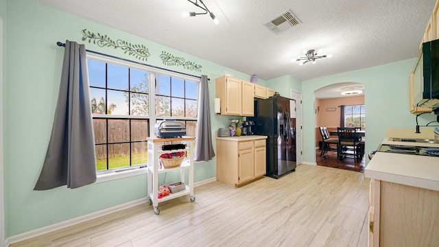 kitchen featuring black fridge, a wealth of natural light, and a textured ceiling