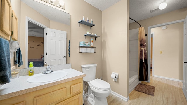 full bathroom featuring vanity, toilet, shower / bath combo with shower curtain, and a textured ceiling