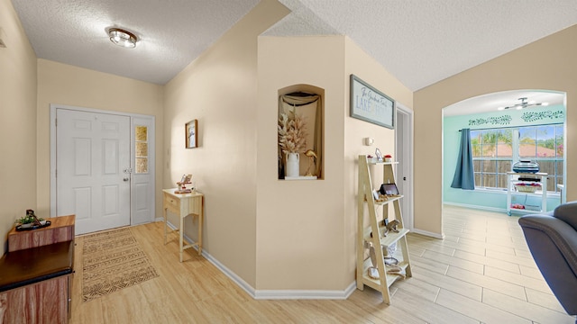 foyer with light wood-type flooring, a textured ceiling, and lofted ceiling