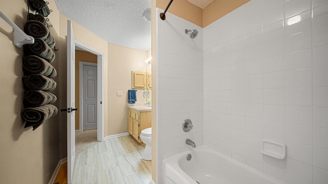 full bathroom featuring vanity, a textured ceiling, tiled shower / bath combo, hardwood / wood-style floors, and toilet