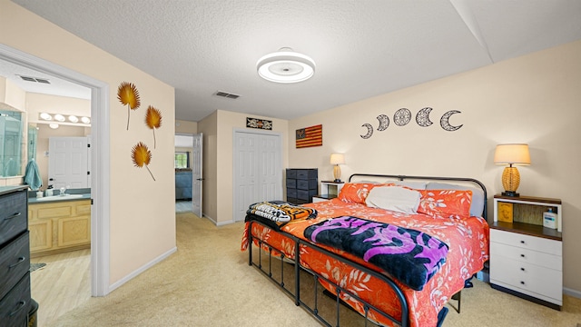 carpeted bedroom featuring a textured ceiling, ensuite bathroom, and a closet