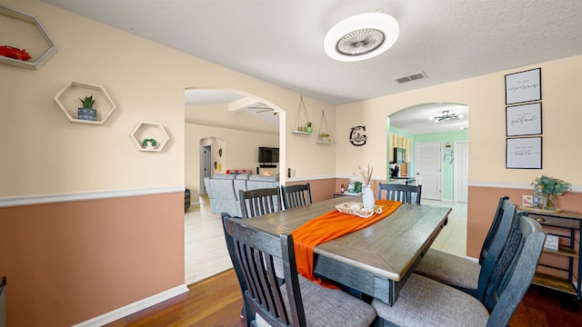 dining space with hardwood / wood-style flooring, a textured ceiling, and an inviting chandelier