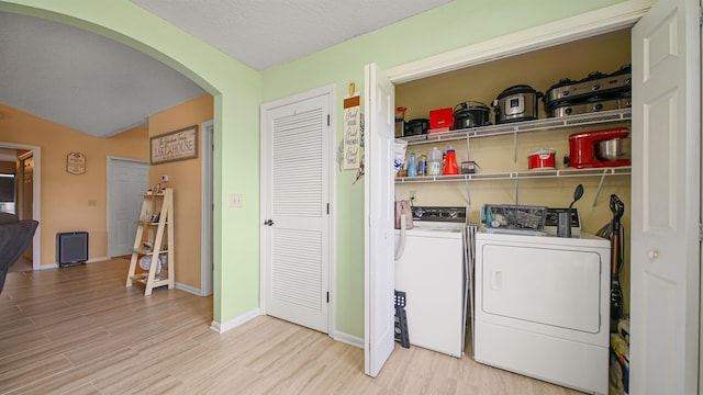 laundry room featuring a textured ceiling, separate washer and dryer, and light hardwood / wood-style flooring